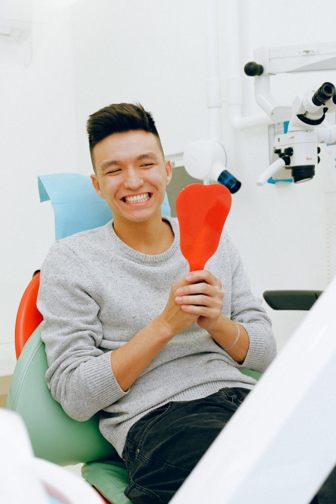 teeth whitening - man smiling into mirror